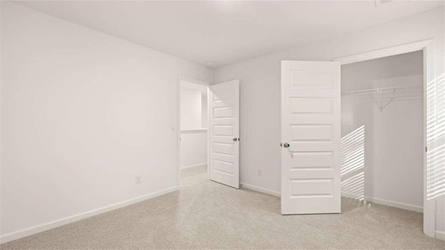 unfurnished bedroom featuring light colored carpet and a closet