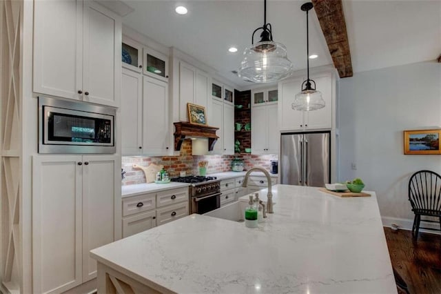 kitchen featuring pendant lighting, a center island with sink, sink, tasteful backsplash, and stainless steel appliances