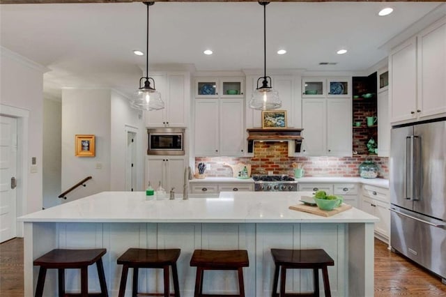 kitchen featuring decorative backsplash, a kitchen island with sink, white cabinets, and appliances with stainless steel finishes