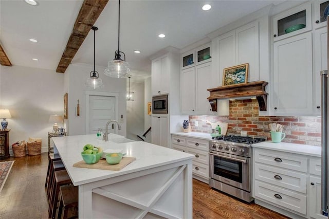 kitchen featuring decorative backsplash, a breakfast bar, stainless steel appliances, sink, and beam ceiling