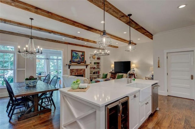 kitchen featuring a kitchen island with sink, beverage cooler, decorative light fixtures, and a brick fireplace