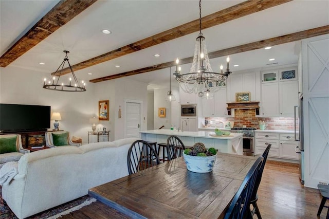 dining room with beam ceiling, light wood-type flooring, and sink