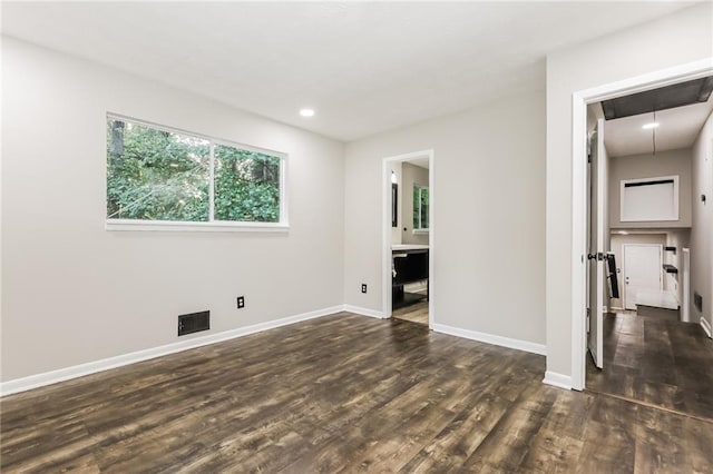 unfurnished bedroom featuring dark wood finished floors, attic access, baseboards, and recessed lighting