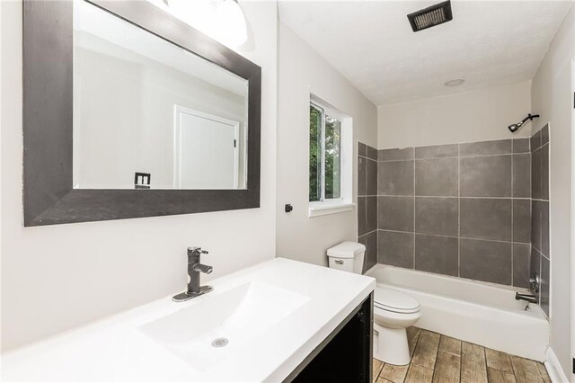 bathroom with toilet, wood finished floors, vanity, and bathing tub / shower combination