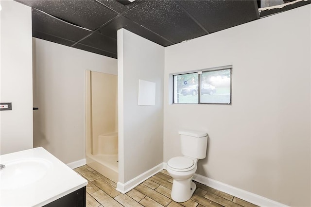 full bath featuring toilet, wood tiled floors, a walk in shower, vanity, and baseboards