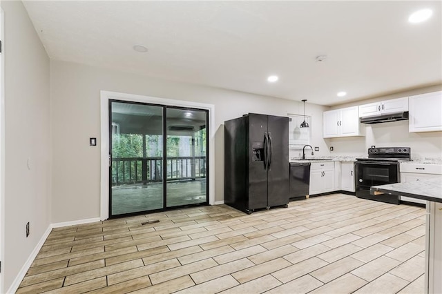 kitchen featuring black appliances, white cabinets, under cabinet range hood, baseboards, and a sink
