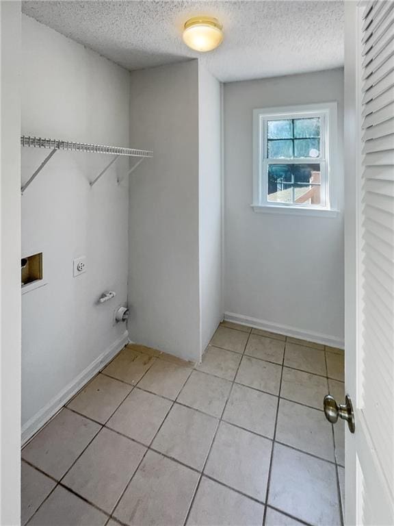 laundry area featuring hookup for a washing machine, light tile patterned floors, electric dryer hookup, and a textured ceiling