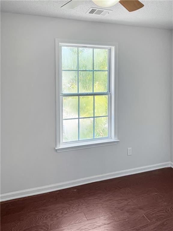 empty room with a textured ceiling, ceiling fan, and dark hardwood / wood-style flooring