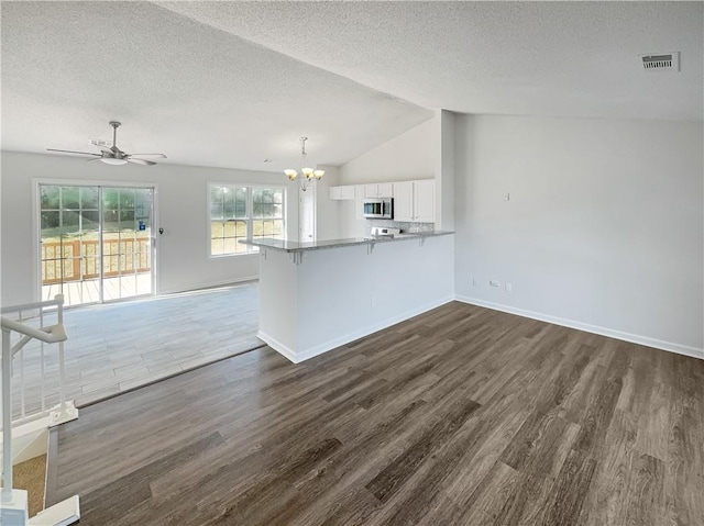 interior space with lofted ceiling, white cabinetry, kitchen peninsula, and dark hardwood / wood-style flooring