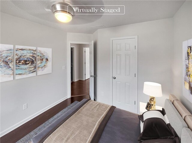 bedroom with ceiling fan, dark hardwood / wood-style floors, and a textured ceiling