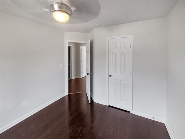 unfurnished bedroom featuring dark wood-type flooring and ceiling fan