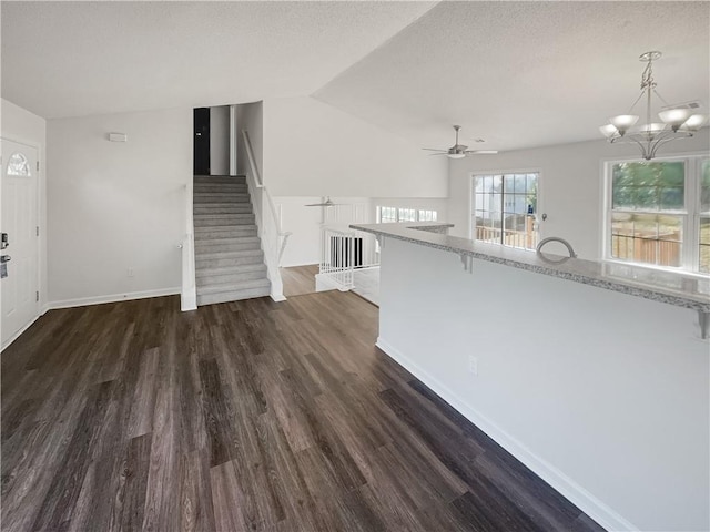 interior space featuring ceiling fan with notable chandelier and dark wood-type flooring