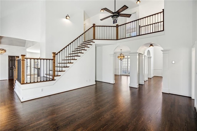 8625 Anchor On Lanier Ct, Gainesville, GA 30506 - unfurnished living room featuring a towering ceiling, a ceiling fan, arched walkways, wood finished floors, and ornate columns
