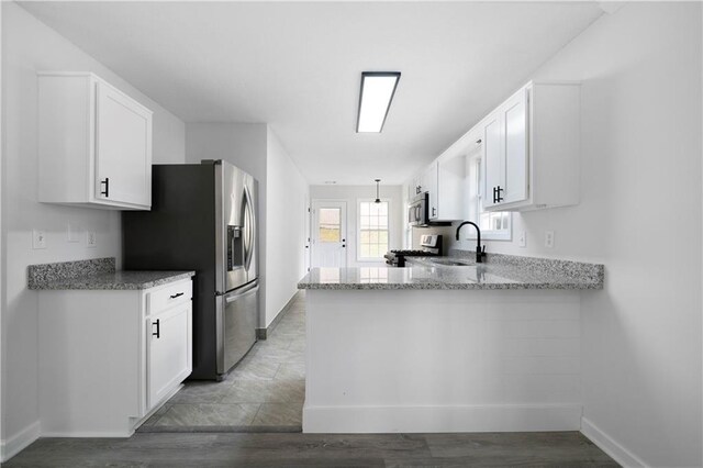 1031 Abercorn Way, Douglasville, GA 30134 - kitchen featuring light stone countertops, stainless steel appliances, white cabinets, a sink, and a peninsula