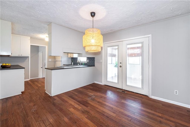 kitchen featuring white cabinetry, dark hardwood / wood-style floors, decorative light fixtures, and french doors