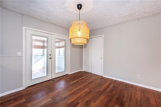 spare room featuring dark hardwood / wood-style floors, a textured ceiling, and french doors