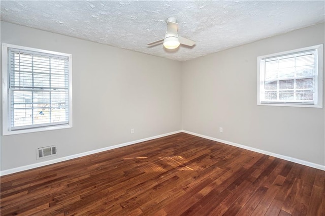 empty room with ceiling fan, dark hardwood / wood-style floors, and a textured ceiling