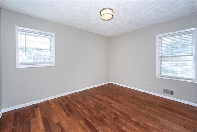 spare room featuring dark wood-type flooring and a textured ceiling