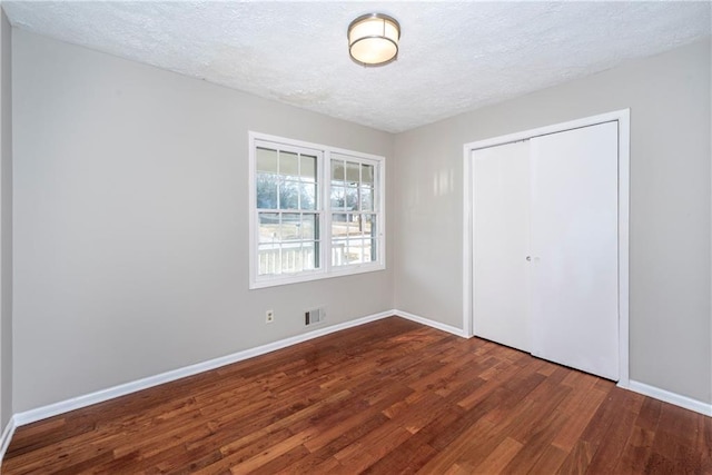 unfurnished bedroom featuring dark hardwood / wood-style flooring, a closet, and a textured ceiling