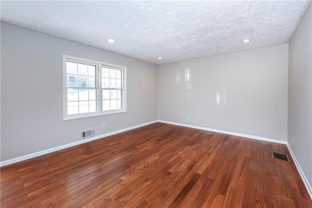 unfurnished room with dark hardwood / wood-style flooring and a textured ceiling