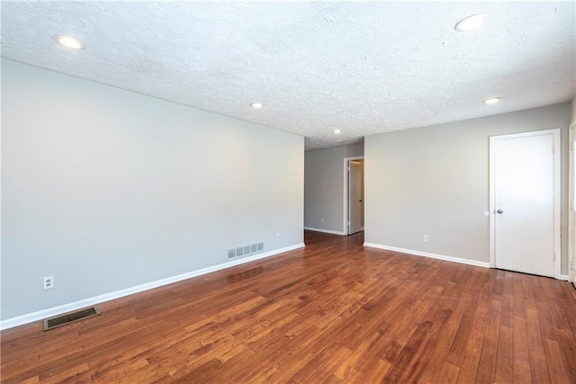 spare room with dark hardwood / wood-style floors and a textured ceiling