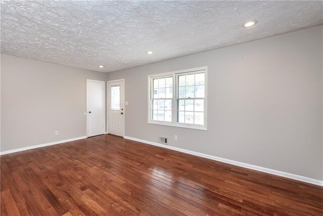 empty room with dark hardwood / wood-style flooring and a textured ceiling