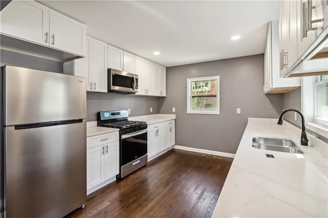 2267 Bryant Dr, East Point, GA 30344 - kitchen with baseboards, dark wood-type flooring, white cabinets, a sink, and appliances with stainless steel finishes