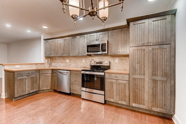 kitchen featuring sink, decorative backsplash, ornamental molding, light hardwood / wood-style floors, and stainless steel appliances