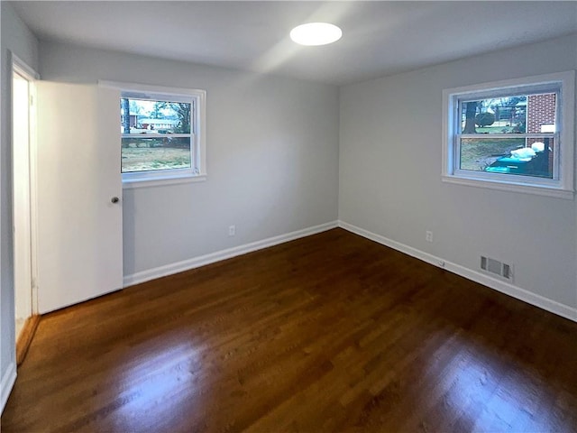 unfurnished bedroom with visible vents, dark wood finished floors, and baseboards