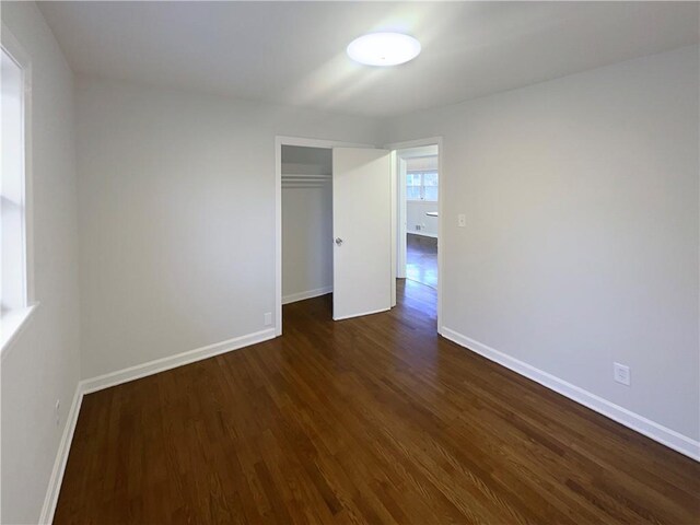 empty room featuring dark wood finished floors and baseboards