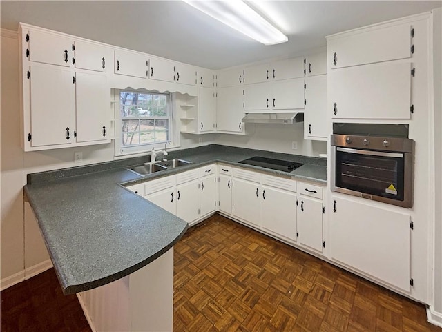 kitchen featuring dark countertops, oven, white cabinetry, and under cabinet range hood