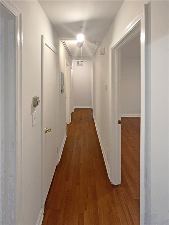 hallway with attic access, dark wood-type flooring, and baseboards