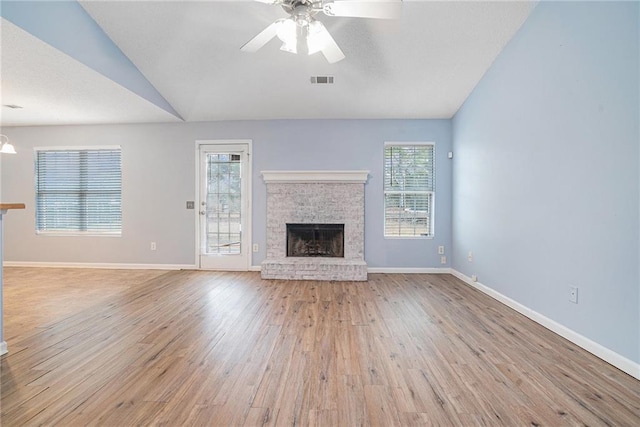 unfurnished living room with light wood-type flooring, a fireplace, ceiling fan, and vaulted ceiling