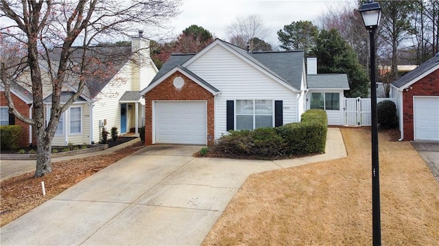 traditional-style house with a garage, brick siding, driveway, a gate, and a chimney