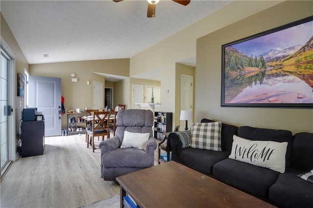 living area featuring light wood-style floors, lofted ceiling, and a ceiling fan