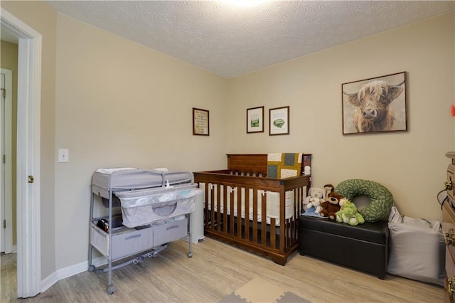 bedroom with a textured ceiling, light wood finished floors, and baseboards