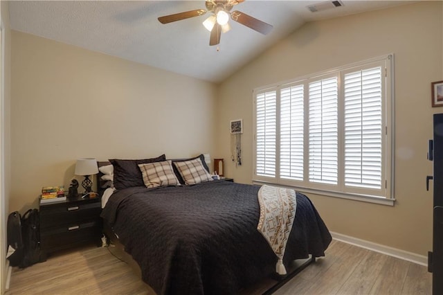 bedroom featuring lofted ceiling, visible vents, a ceiling fan, light wood-type flooring, and baseboards