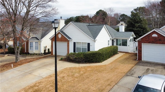 view of front of home featuring driveway, a chimney, and an attached garage