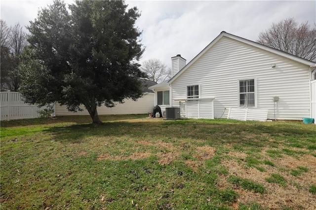 exterior space with a chimney, fence, a lawn, and cooling unit