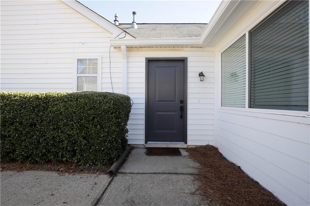 entrance to property featuring a shingled roof