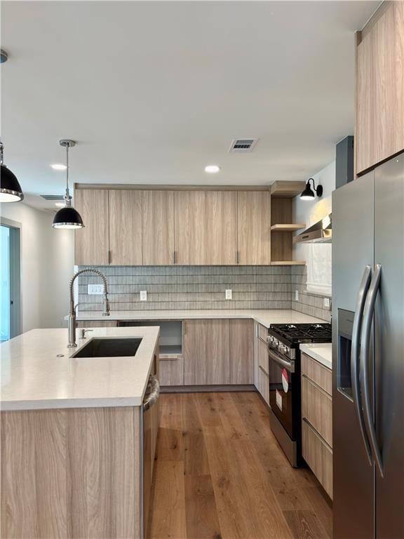 kitchen featuring light brown cabinets, a sink, stainless steel appliances, light countertops, and modern cabinets