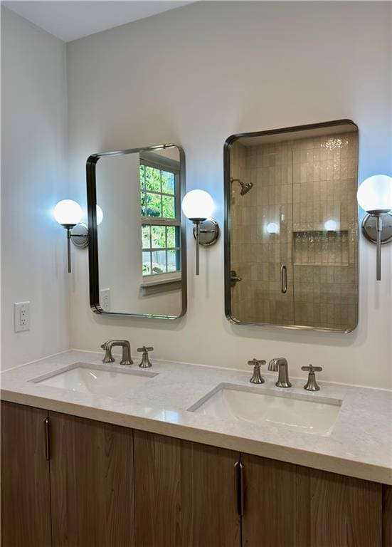 bathroom with a shower stall, double vanity, and a sink