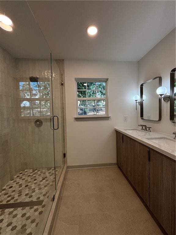 full bath featuring double vanity, a shower stall, baseboards, and a sink