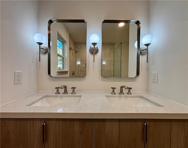 bathroom with double vanity, a tile shower, and a sink