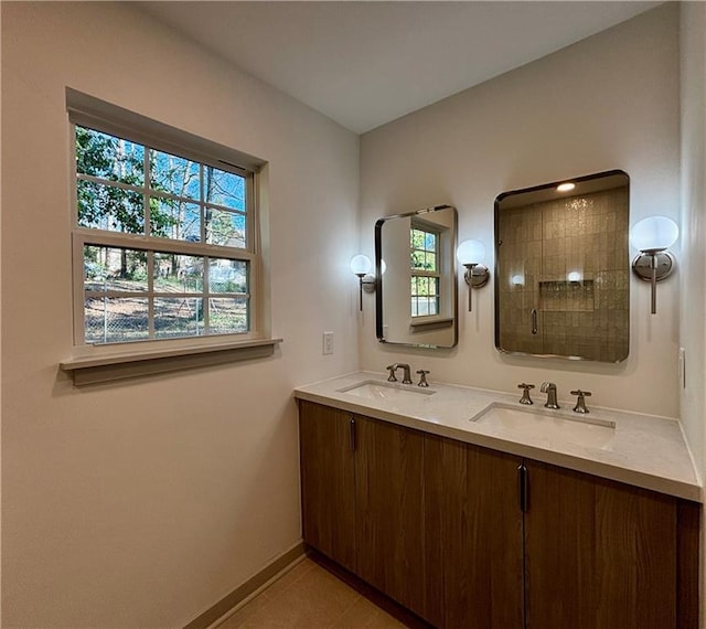 bathroom with a healthy amount of sunlight, tiled shower, and a sink