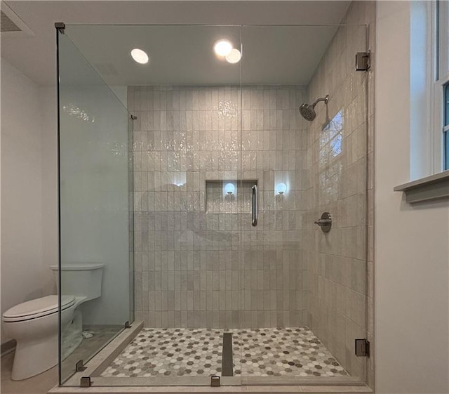 bathroom with tile patterned flooring, toilet, and a stall shower