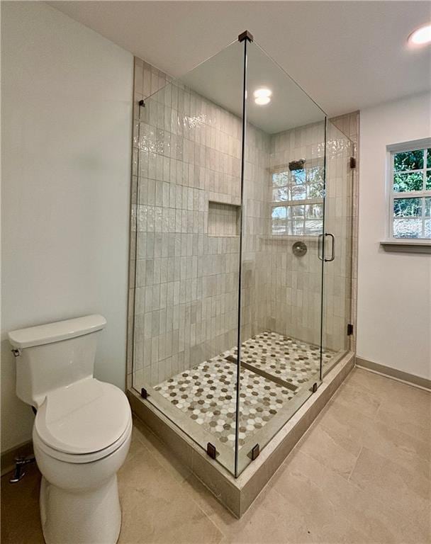 full bathroom featuring baseboards, toilet, and a shower stall