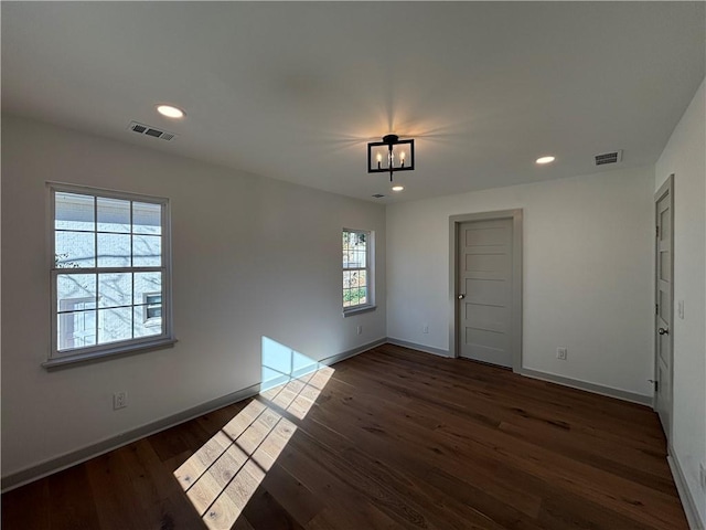 spare room featuring visible vents, a healthy amount of sunlight, and dark wood-style flooring