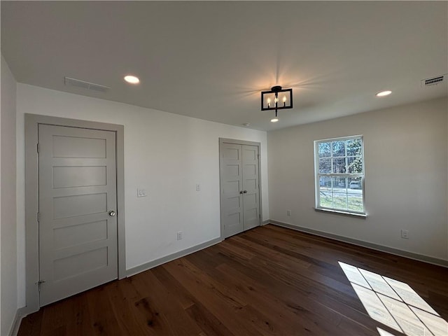 empty room featuring visible vents, baseboards, and dark wood-type flooring