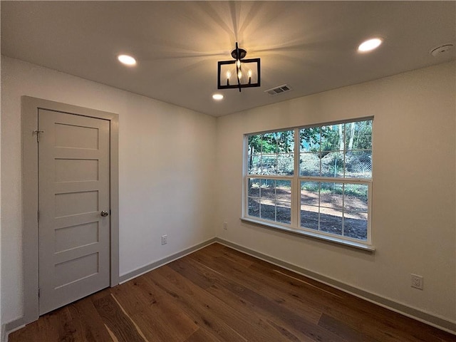 empty room featuring recessed lighting, visible vents, dark wood-type flooring, and a chandelier